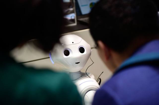 The robot "Pepper" speaks with visitors at the IBM stand at a technology trade fair (Credit: Alexander Koerner/Getty Images)