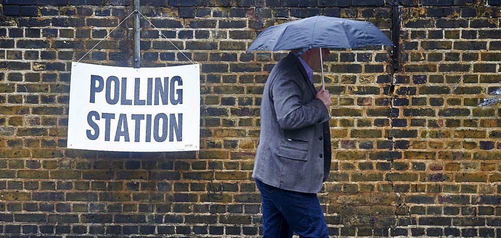 A man shelters from the rain as he arrives to vote. Credit: Getty.