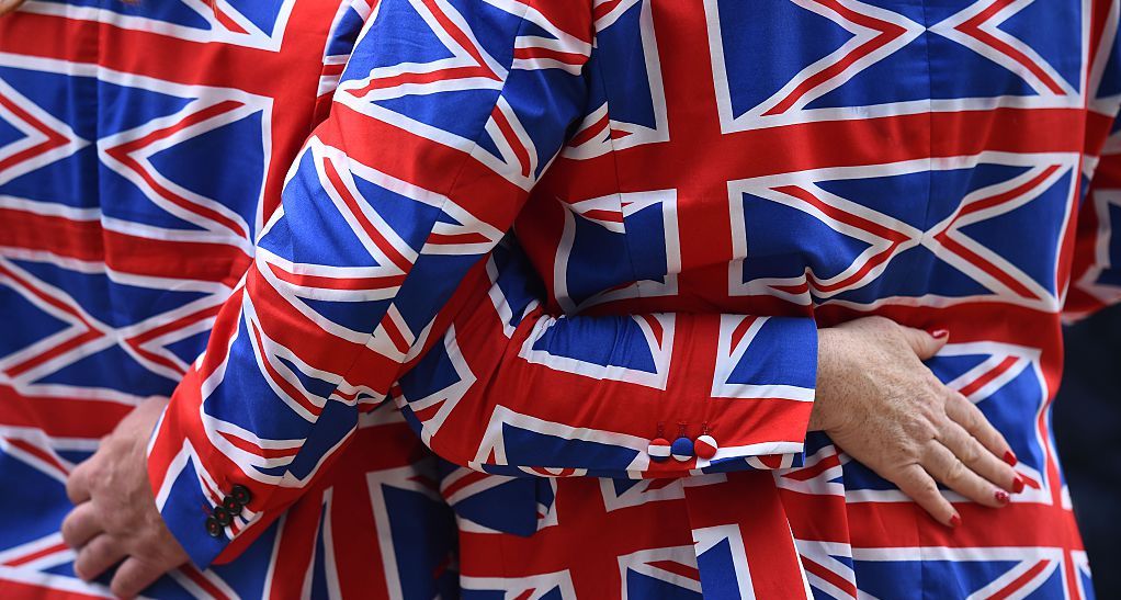 A couple wear matching Union Jack suits outside Buckingham Palace. Credit: Getty