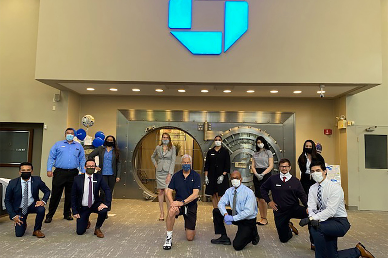 JPMorgan CEO Jamie Dimon (c) takes a knee while visiting a Chase branch 
