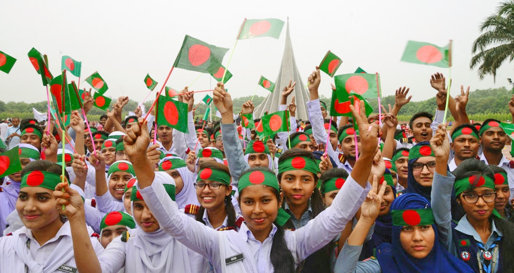 Bangladeshi people gather with flags and flowers to show their respect during the celebration of the country's Independence Day