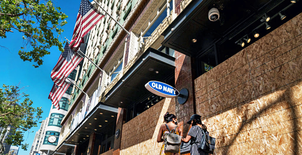 Locals walk past a boarded up Old Navy Inc. store in San Francisco, California. Credit: Getty