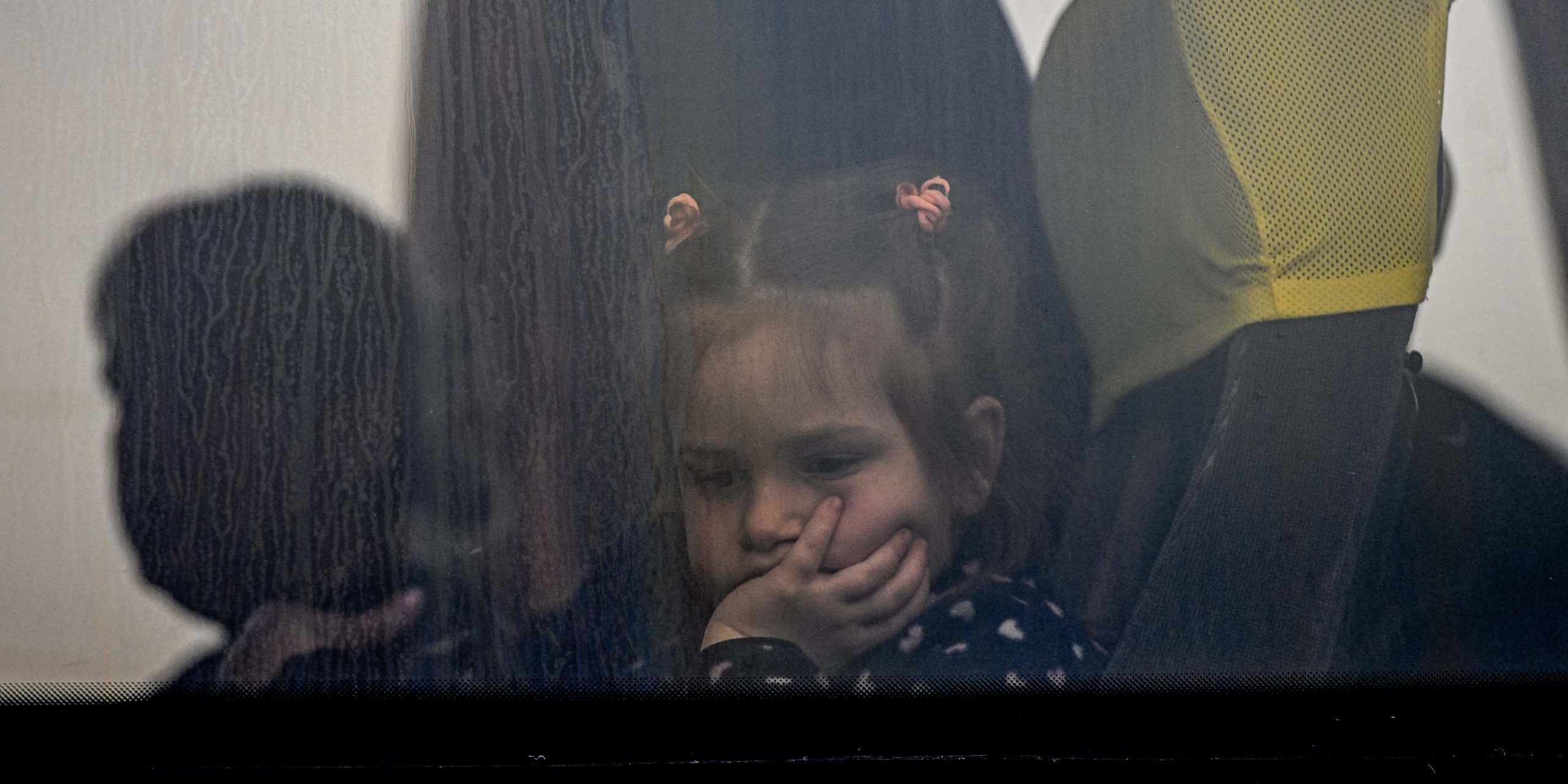 A child refugee from Ukraine looks out a bus window on March 25, 2022 (Photo by DANIEL MIHAILESCU/AFP via Getty Images)