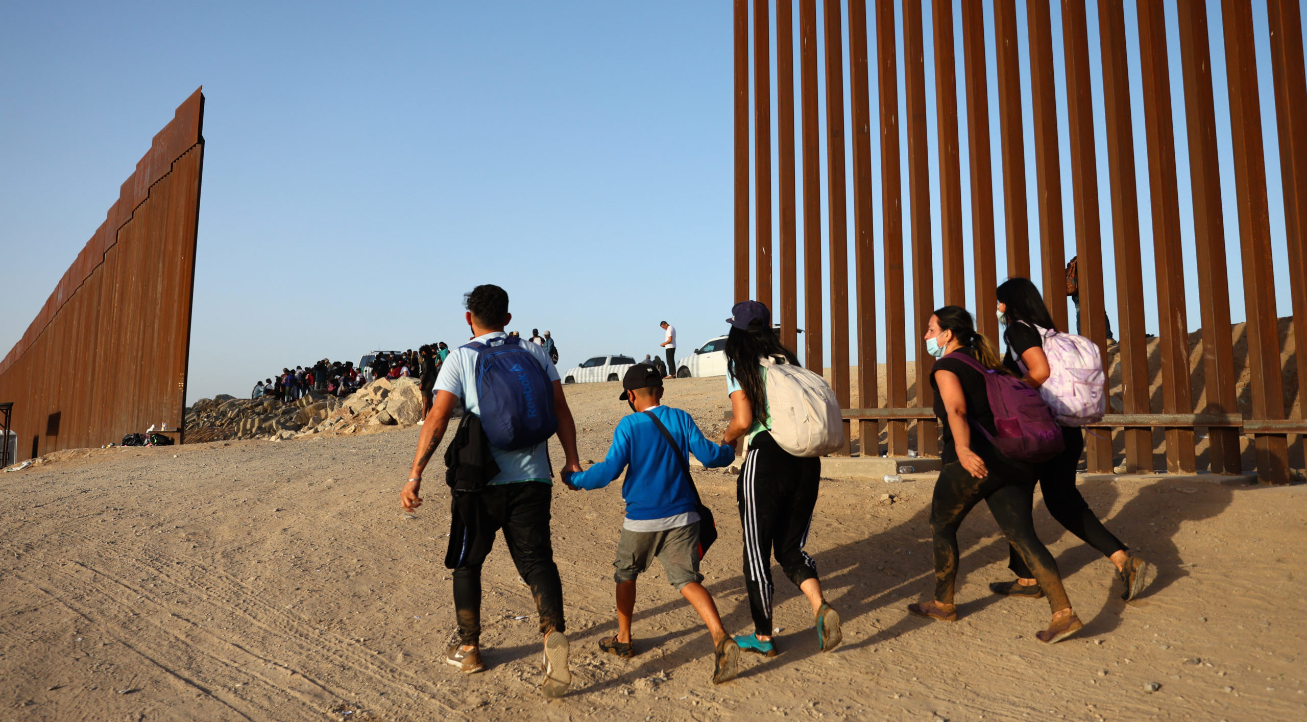 Immigrants cross through a gap in Yuma, Arizona (Photo by Mario Tama/Getty Images)