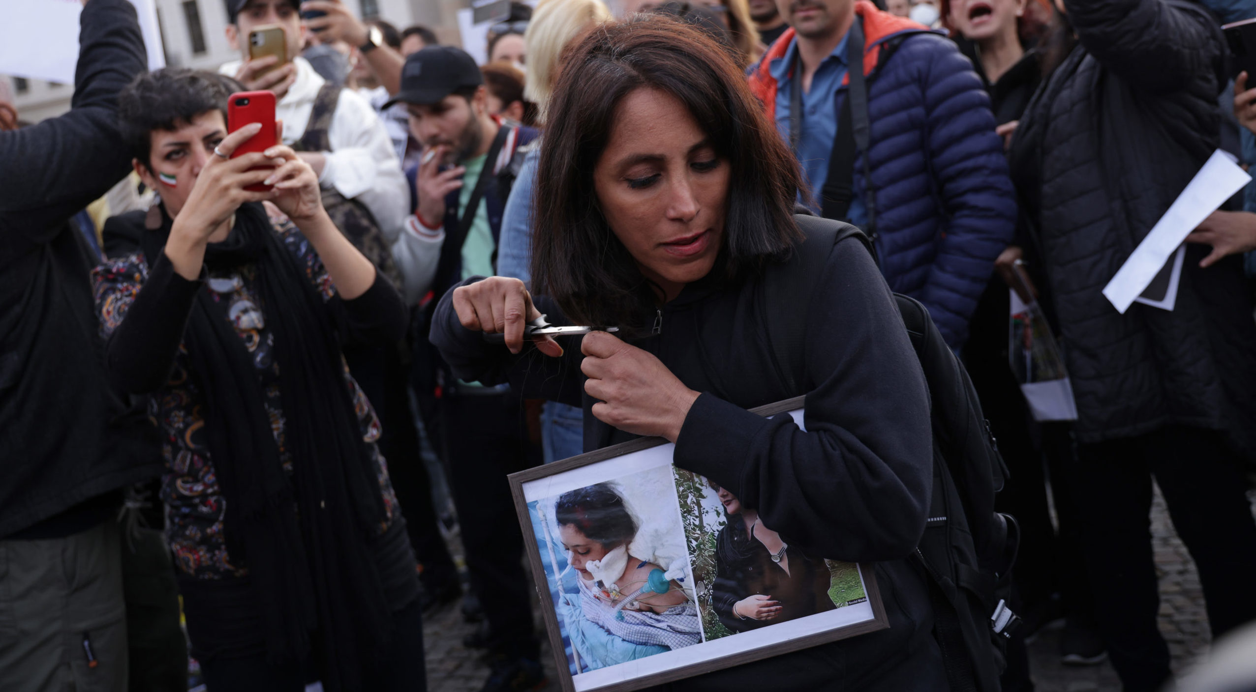 A female protester cuts her hair with scissors as an act of solidarity with women in Iran 