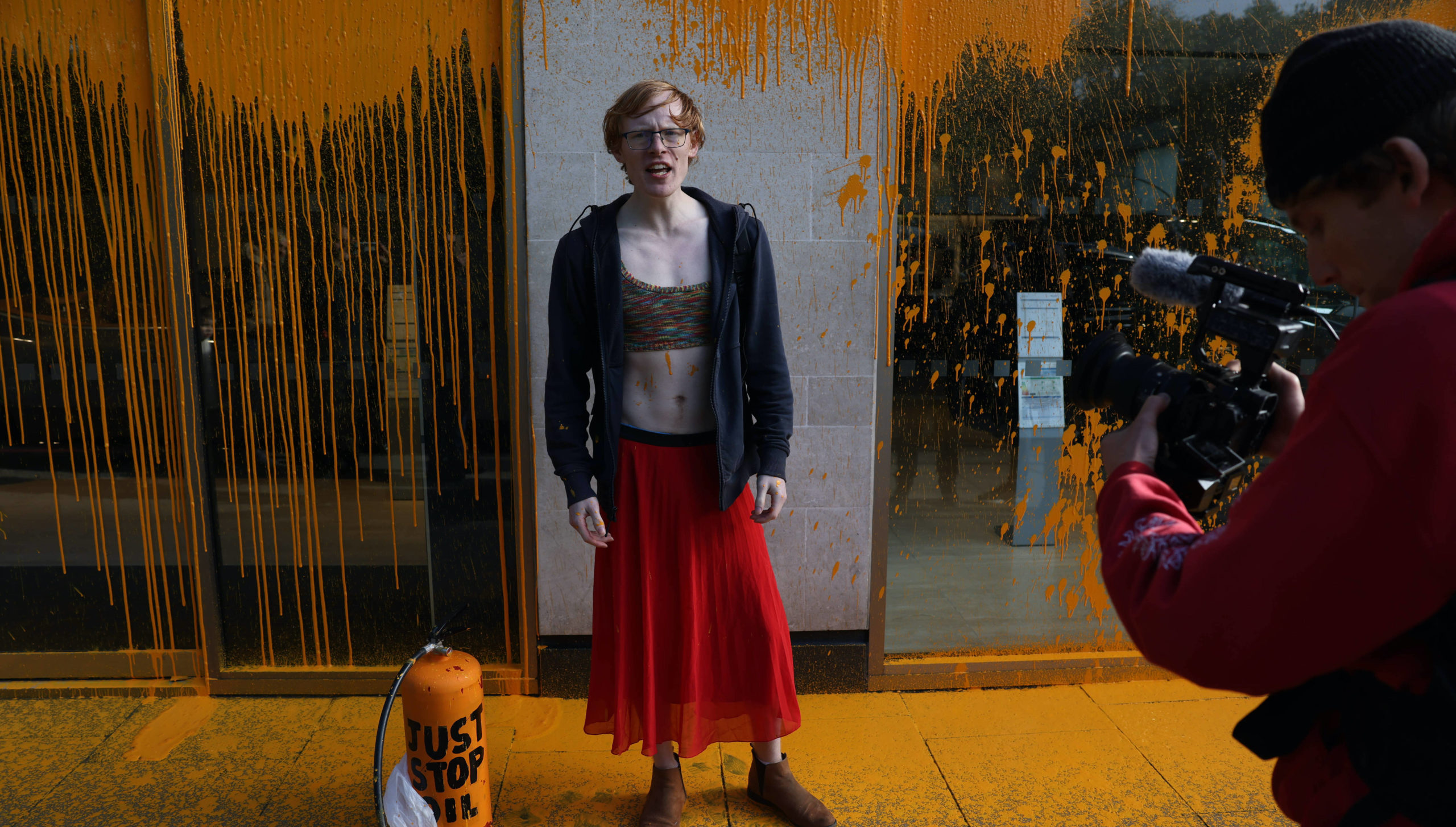 A Just Stop Oil protestor sprays an orange substance on the Aston Martin Store in Mayfair