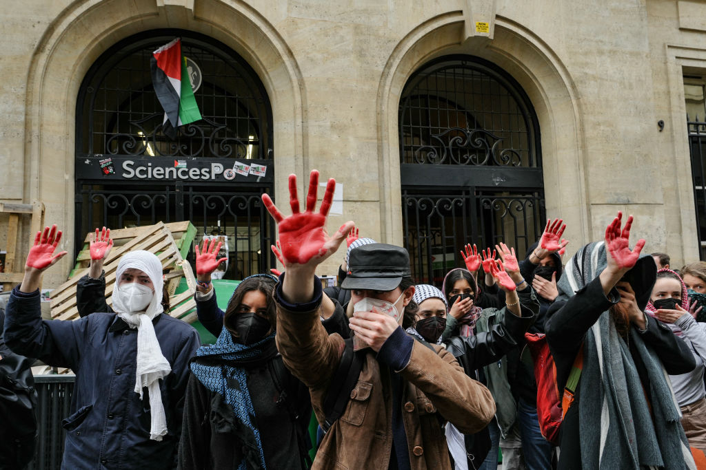 Students with red paint on their hands protest outside Sciences Po on Friday. Credit: Getty