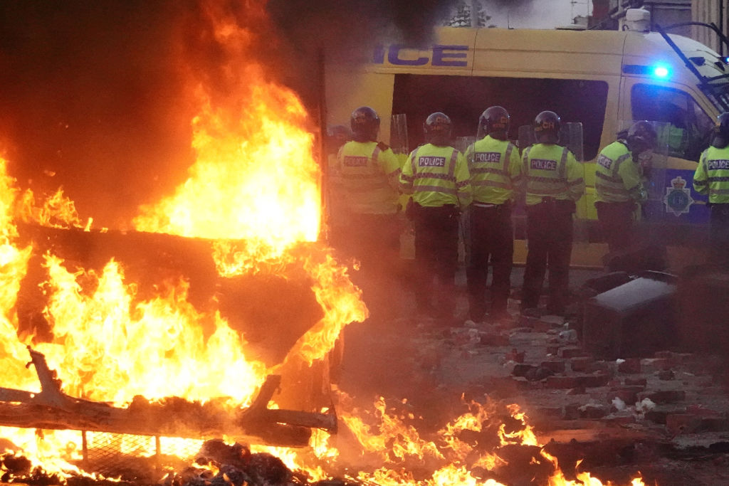 Riot police hold back protesters near a burning police vehicle in Southport last night. Credit: Getty
