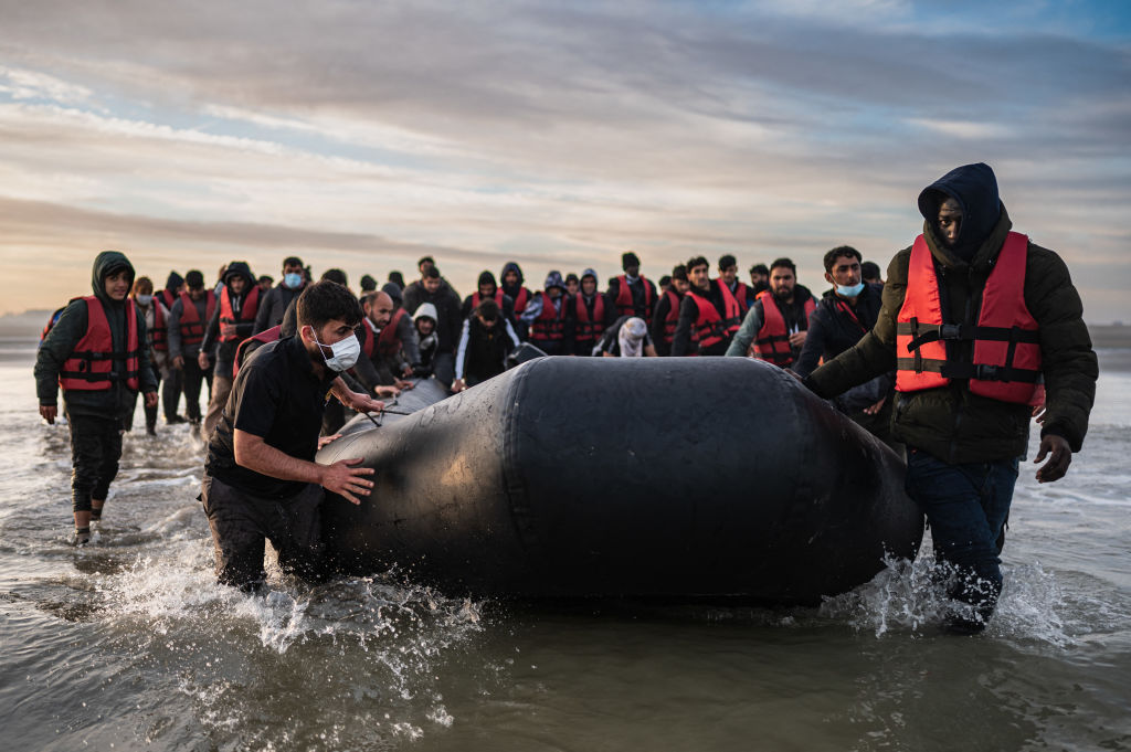 Migrants move a smuggling boat before attempting a crossing of the English Channel. Credit: Getty