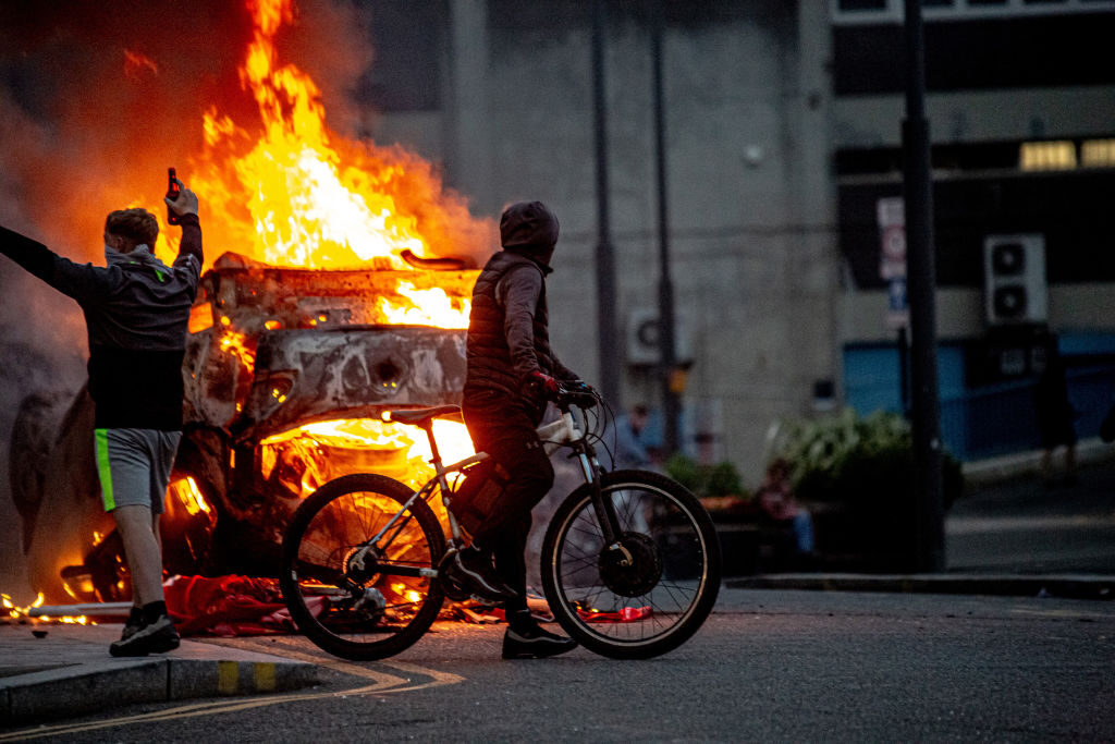 A police car is set on fire during last summer's riots across England. Credit: Getty